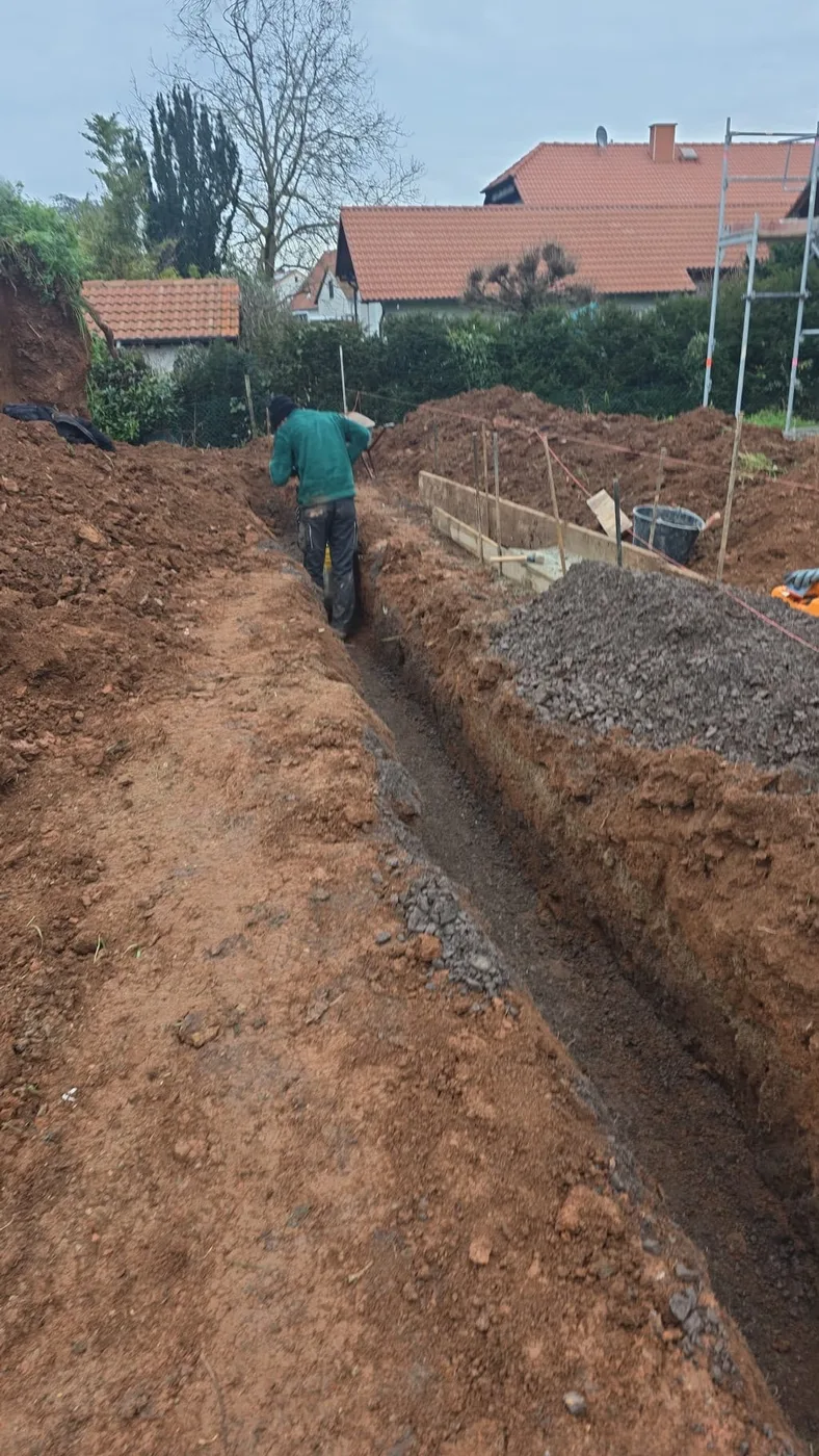 Royal-Garden-Mitarbeiter hebt einen Drainagegraben auf einer Gartenbaustelle aus