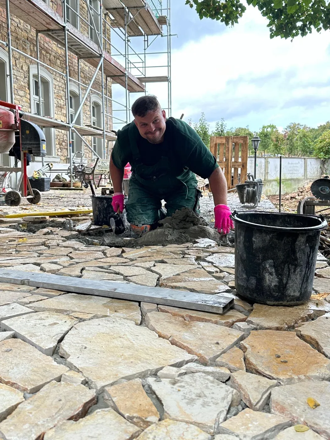 Royal-Garden-Mitarbeiter verlegt Natursteinplatten für eine neue Terrasse